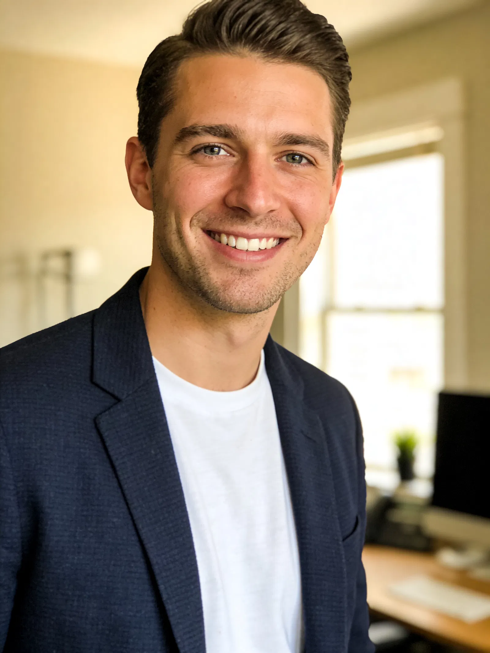 White man in blazer smiling in home office portrait