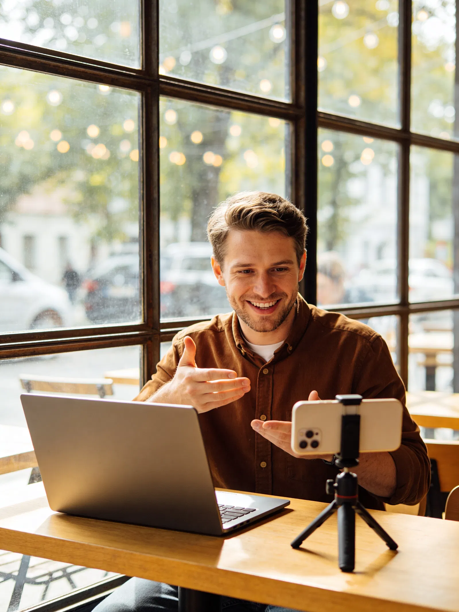 White man recording a Reel at a café with laptop and mini tripod