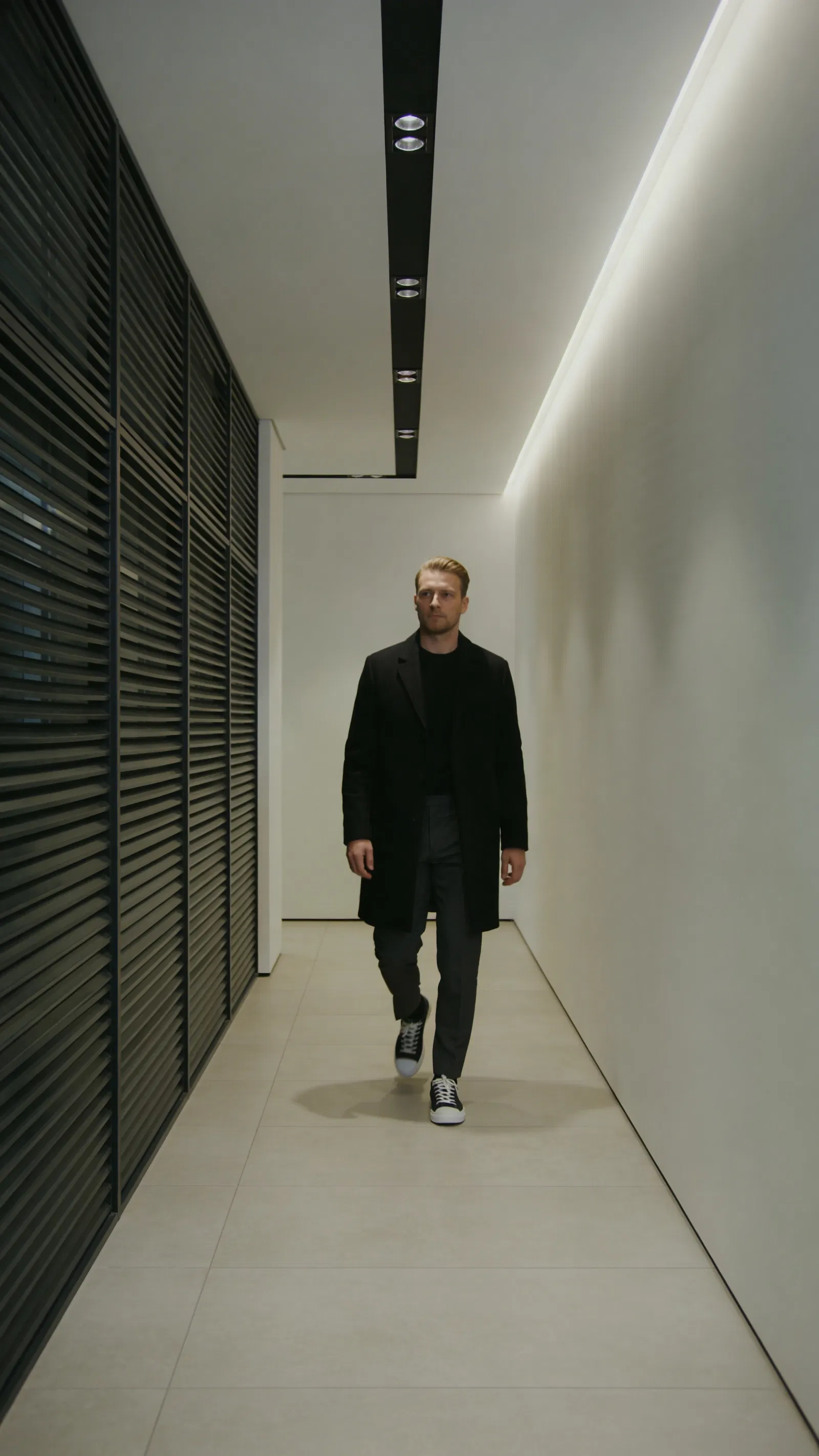 White man walking in modern hallway full-body editorial photo