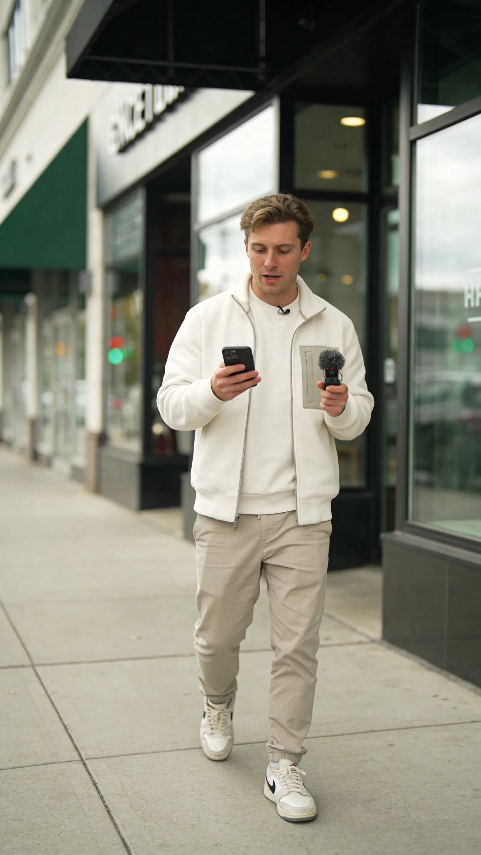 White man walking with phone and mic, candid creator-style social photo